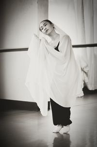 Full length of woman with white textile standing on floor