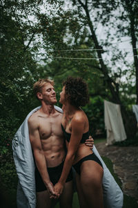 Young couple standing against trees