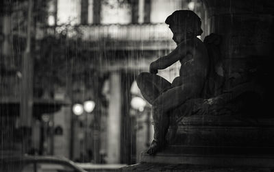 Statue of man sitting against building