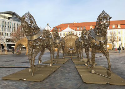 Statues on street amidst buildings in city against sky