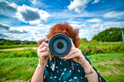 Portrait of man photographing camera against sky