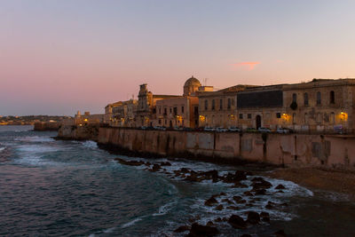 View of ortigia island by sea against sky during sunset