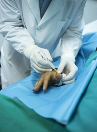 Midsection of doctor injecting hand