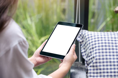 Midsection of woman holding digital tablet while sitting outdoors