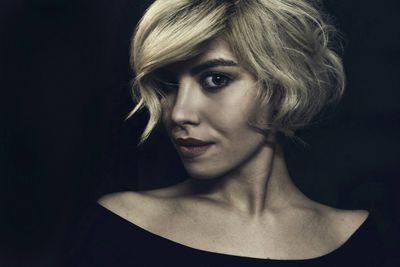 Portrait of young woman against black background