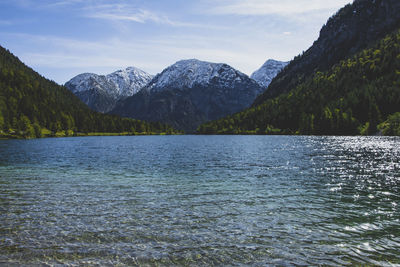 Scenic view of river by mountains against sky