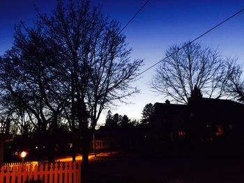 Bare trees against sky at sunset