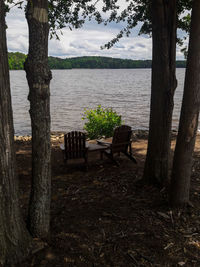 Empty bench by lake against sky