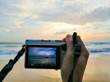 Man photographing on sea at sunset