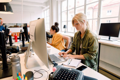 Business professionals working while sitting at desk in office