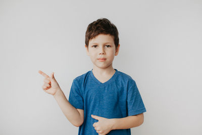 A preschool boy in a blue t-shirt on a light background shows a thumbs up. high quality photo