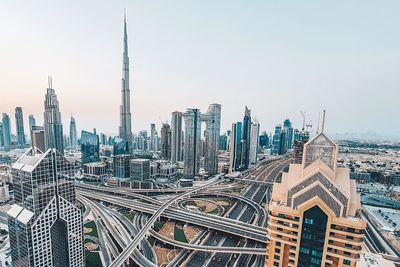 Modern buildings in dubai city burj khalifa and multilevel road junctions against clear sky