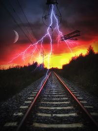 Railroad tracks against sky at night