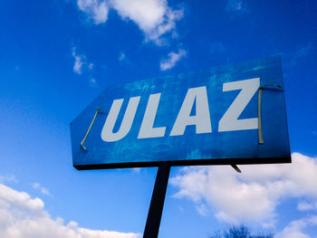 Low angle view of sign board against blue sky