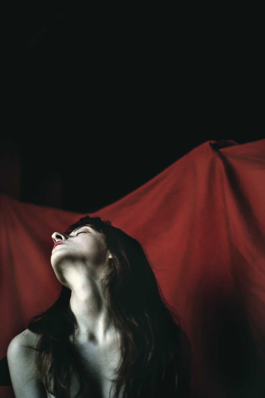 one person, lifestyles, copy space, looking, indoors, young adult, young women, front view, women, real people, adult, looking away, studio shot, red, eyes closed, leisure activity, long hair, black background, beautiful woman, hairstyle, contemplation