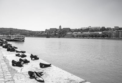 Boats in river by buildings against clear sky