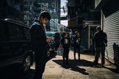 People standing on street amidst buildings in city