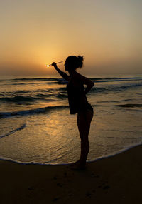 Full length of woman at beach during sunset