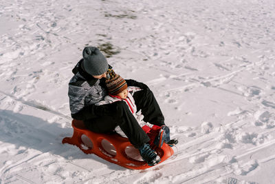 Rear view of woman sitting on snow