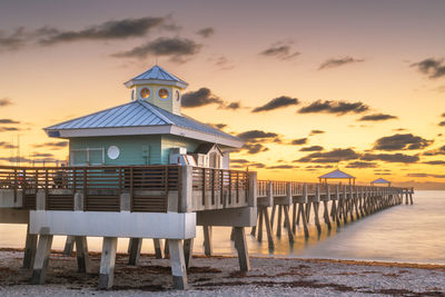 Pier over sea against sky during sunset