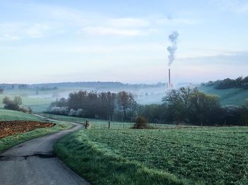 Smoke emitting from chimney on field against sky