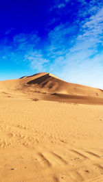 Sand dunes in desert against blue sky