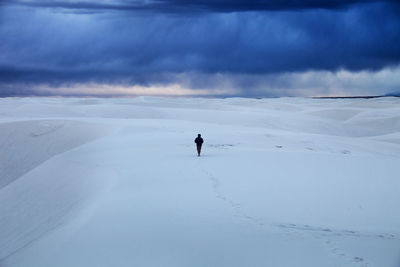 Man standing on snow covered landscape against sky