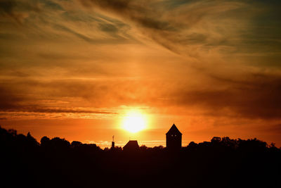Silhouette buildings against sky during sunset