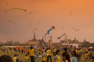 Crowd kite flying against sky during sunset in city during festival