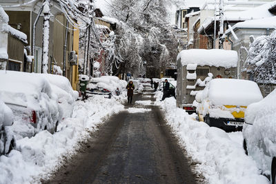 Snow covered street amidst buildings in city