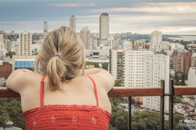 Rear view of woman with cityscape against sky