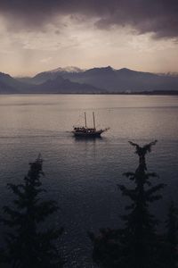 Silhouette sailboat in sea against sky during sunset