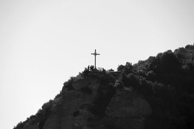 Low angle view of cross on rock against sky