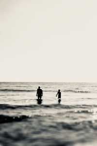 Silhouette people on beach against clear sky