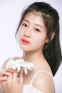 Portrait of woman holding flower against white background