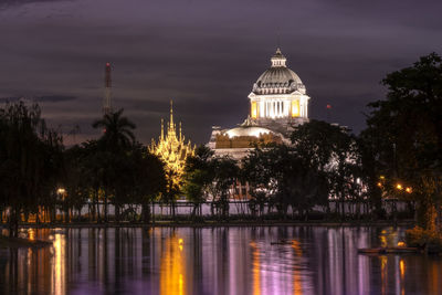 Illuminated building against sky with city in background