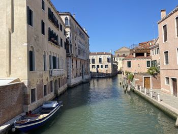 Canal passing through buildings against sky