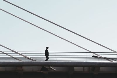 Low angle view of man standing on bridge against sky