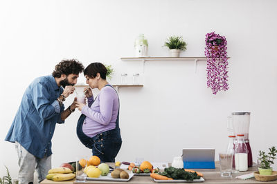 Couple drinking glass of healthy fruit smoothie together in the kitchen