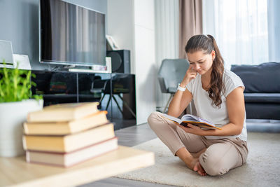 Side view of young woman using mobile phone at home