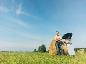 Man and woman standing on field against sky