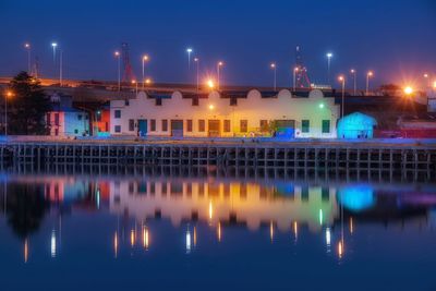 Illuminated industrial buildings with reflection on lake at night