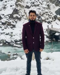 Portrait of young man standing on snow covered field