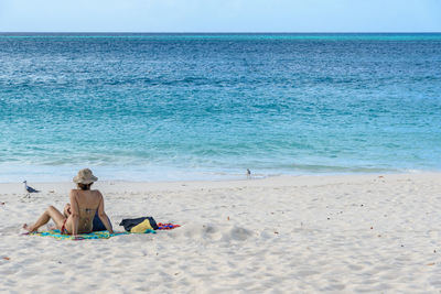 Man sitting on beach against sky