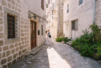 Woman standing on footpath amidst buildings