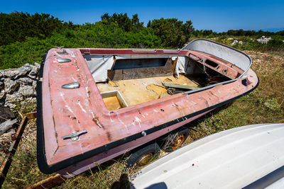 Abandoned boats on field against clear blue sky during sunny day