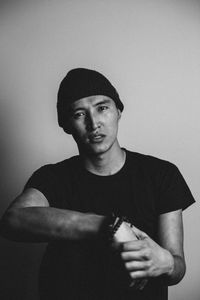 Portrait of young man standing against wall