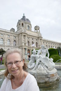 Smiling mature woman standing against statues at hofburg palace