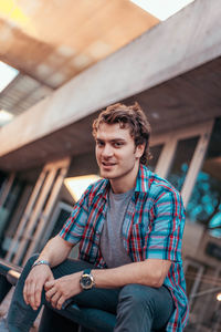 Young man looking away while sitting outdoors