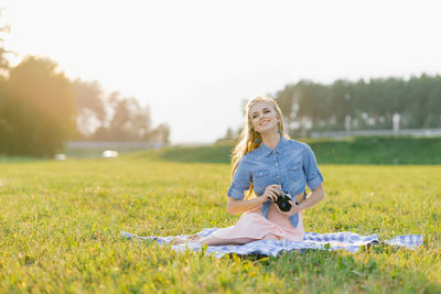 Attractive young woman with a camera in her hands is resting and taking pictures outdoors person
